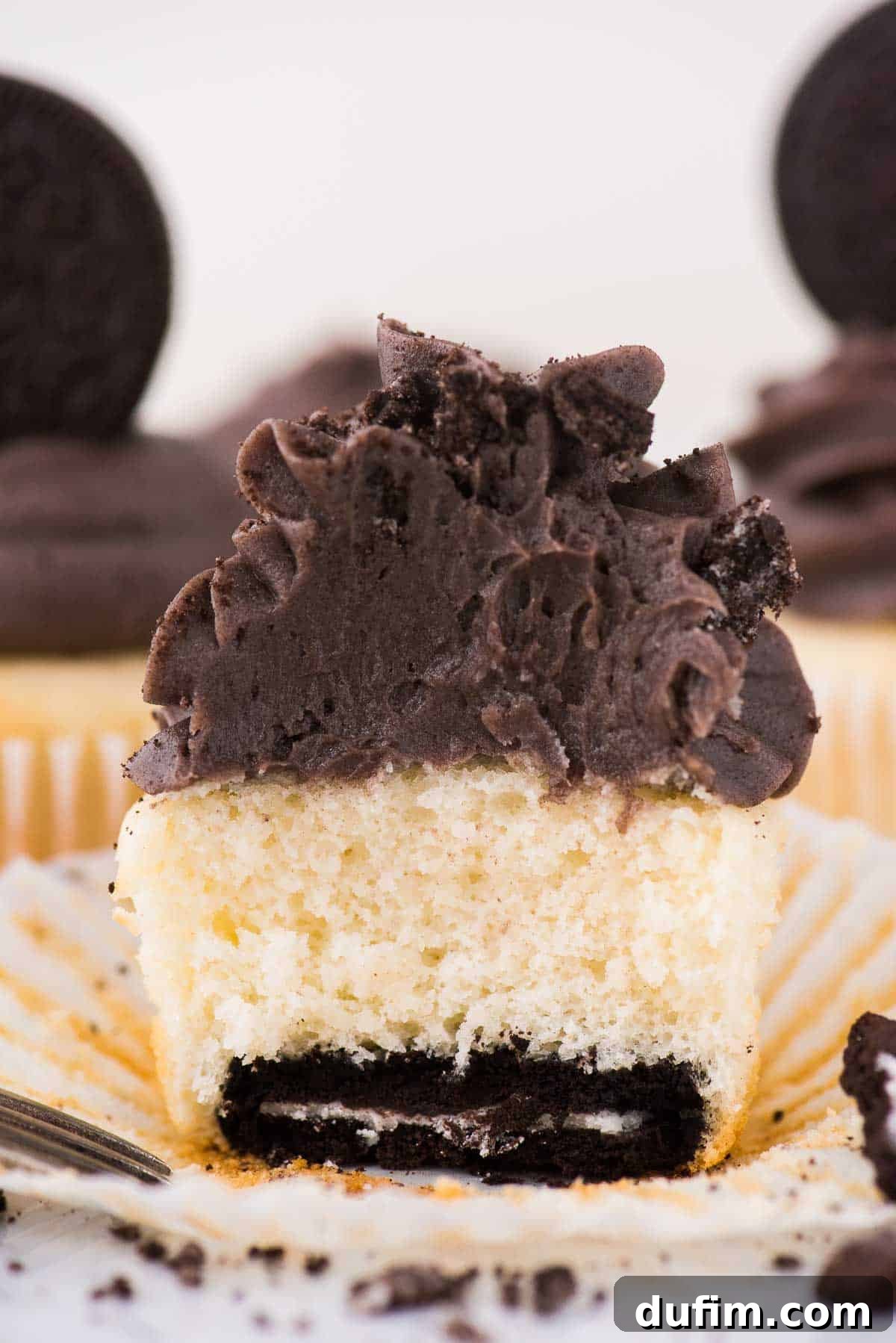 Oreo Cookie Crust Cupcakes 5 Vanilla Oreo bottom cupcake cut in half, revealing the whole Oreo cookie at the base, on a white background