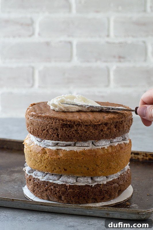 Close-up of a slice of Puppy Chow Cake showing distinct layers of chocolate cake, peanut butter cake, buttercream, and puppy chow pieces.