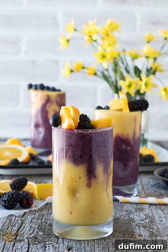 Close-up of a perfectly layered Hawaiian Berry Smoothie, showcasing the distinct orange and purple layers, ready to be enjoyed.
