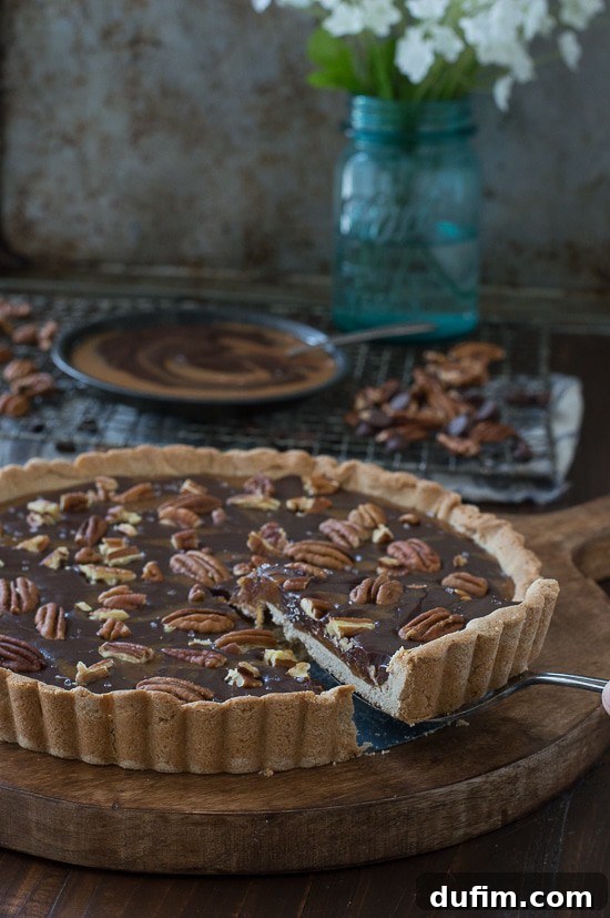 A tantalizing cross-section of a Turtle Tart slice, highlighting the perfectly baked, slightly chewy crust, the gooey caramel center, and the rich chocolate ganache topping with crunchy pecans.