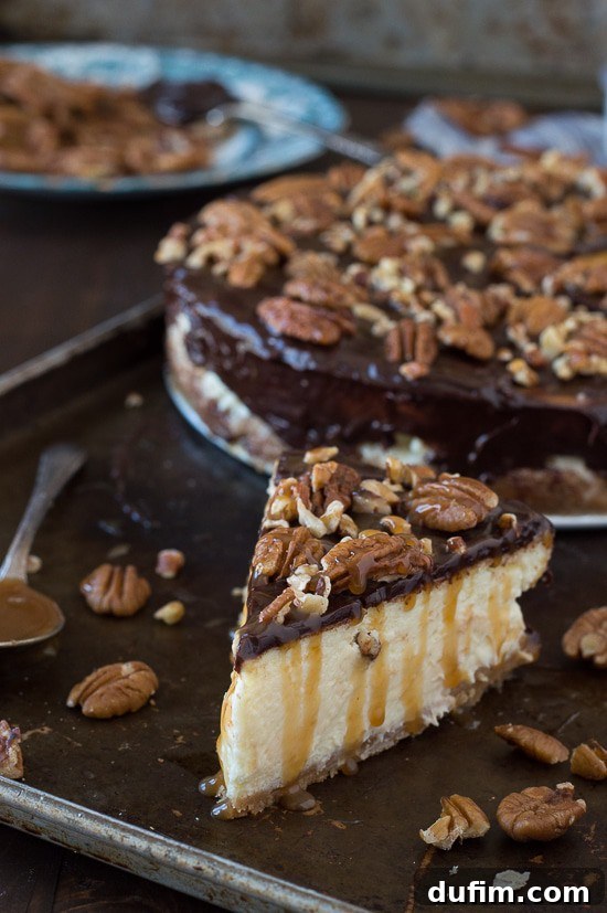 This is the best turtle cheesecake! It’s rich and so creamy. Topped with chocolate ganache, pecans and caramel sauce. A slice of turtle cheesecake on a white plate with a fork.