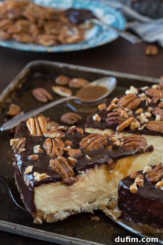 Close-up of a slice of turtle cheesecake on a white plate, showcasing the layers of crust, creamy filling, chocolate ganache, and caramel drizzle.