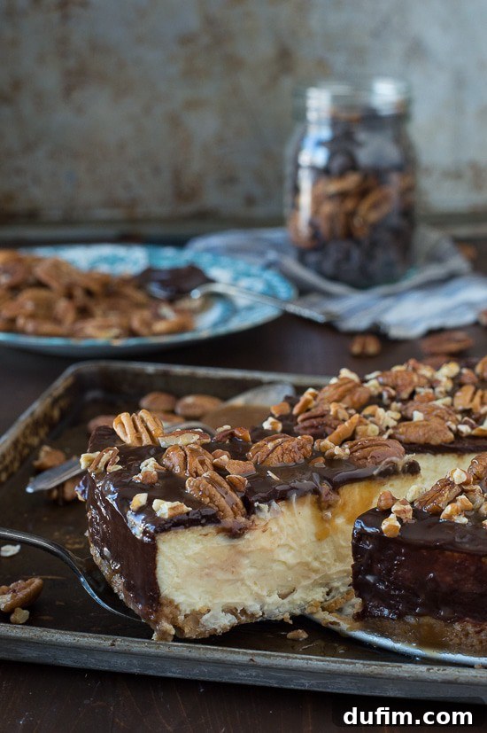 A slice of turtle cheesecake on a plate, garnished with a few whole pecans, showing its delicious layers.