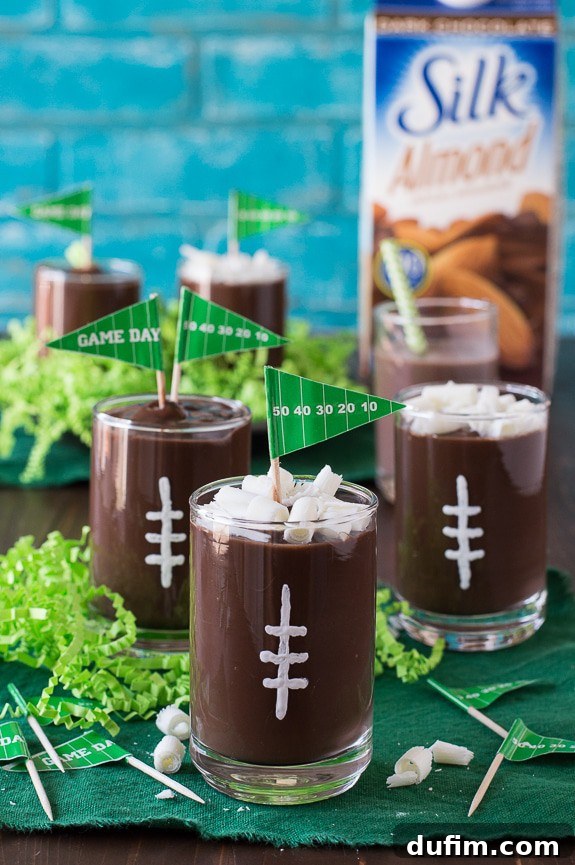 A close-up of a football pudding cup with a 'Game Day' flag, showcasing the intricate white laces and chocolate curls.