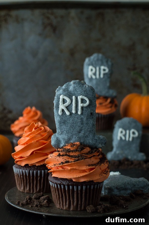 Close-up of a tombstone cookie cutter next to festive Halloween cookie cutters and decorations, hinting at the creative process behind these spooky treats.