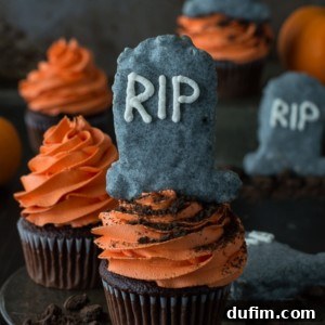 Delicious chocolate Halloween tombstone cupcakes topped with Rice Krispie treat tombstones and orange buttercream.