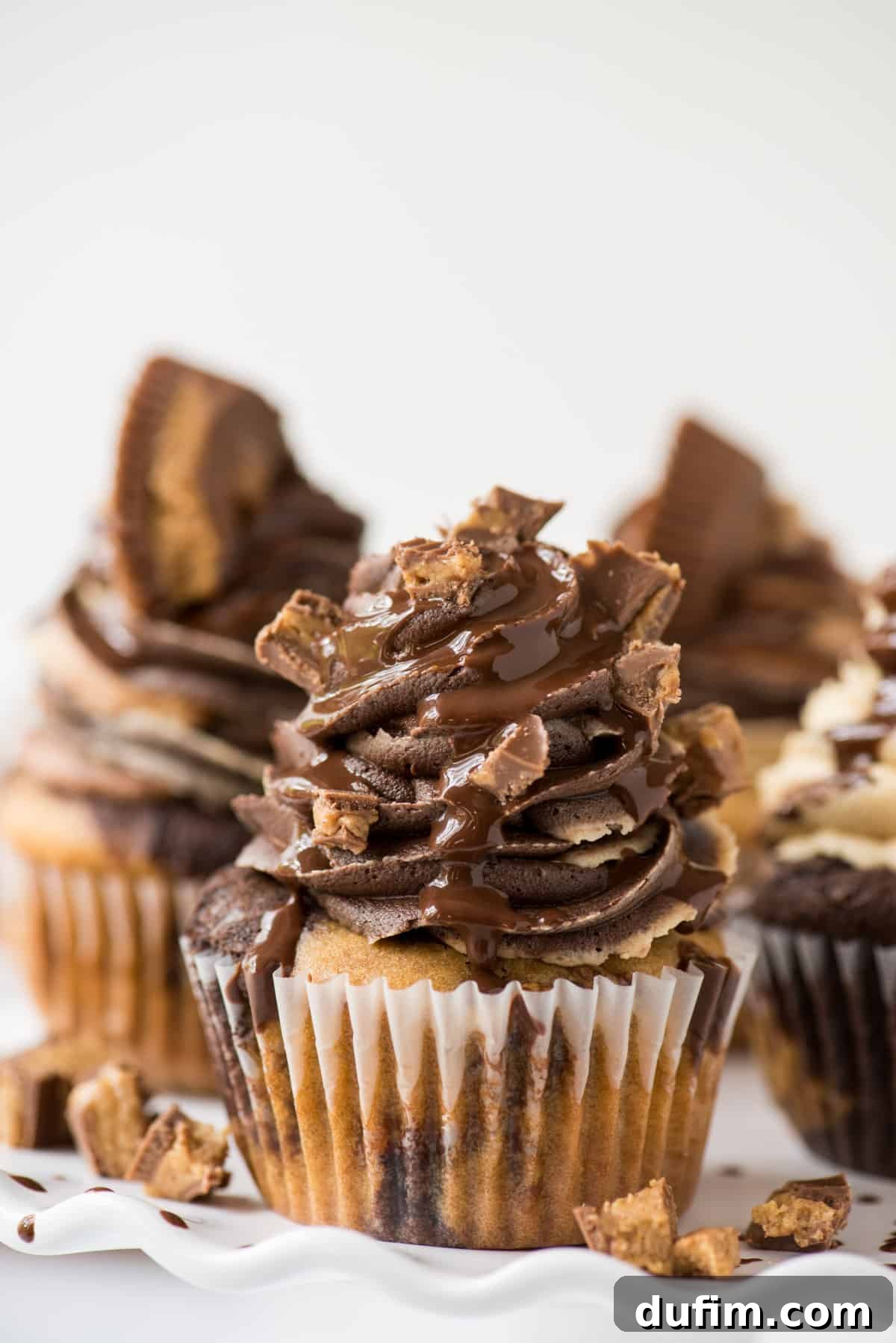 chocolate peanut butter reese’s cupcakes on white tray with white background
