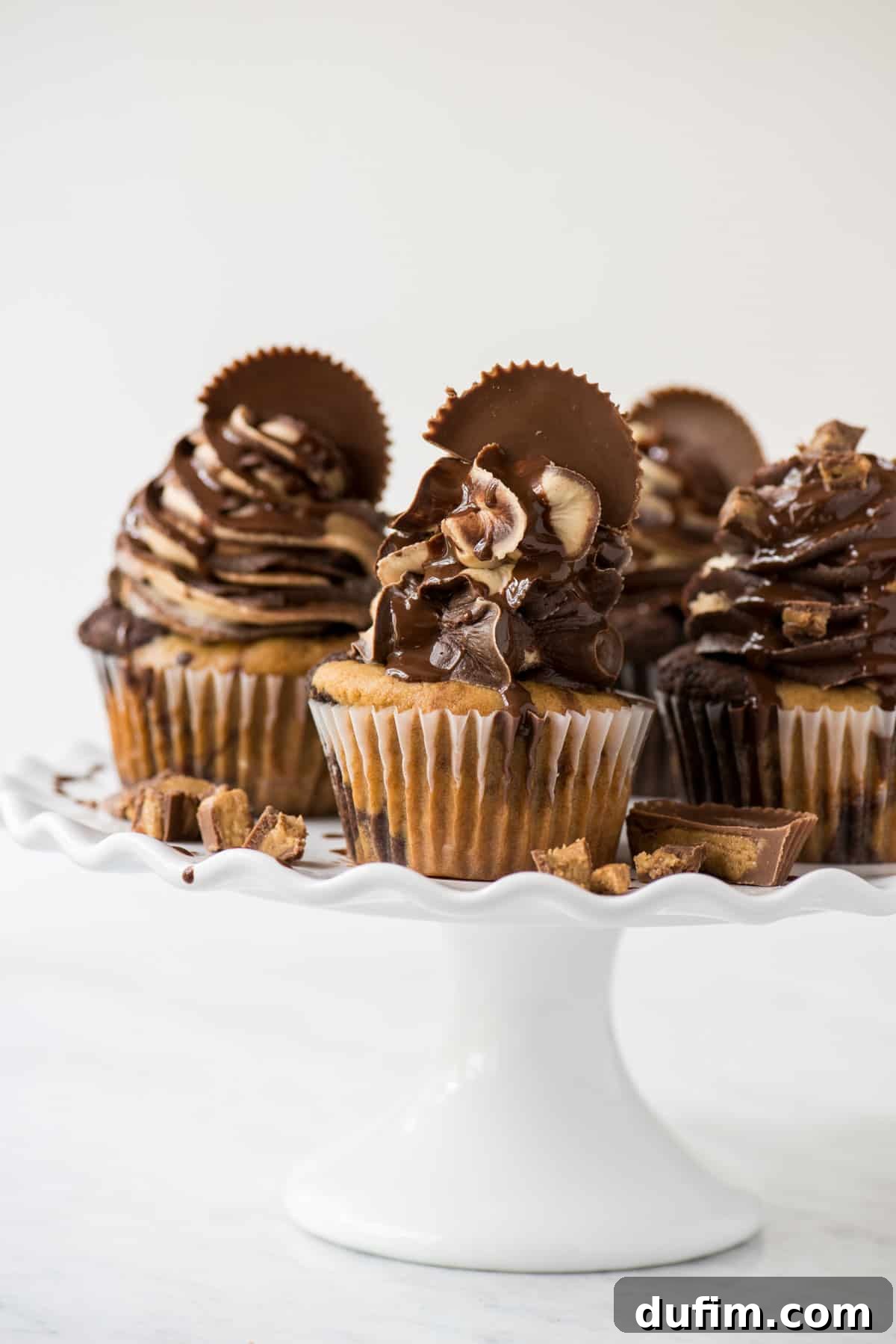 chocolate peanut butter reese’s cupcakes on white tray with white background