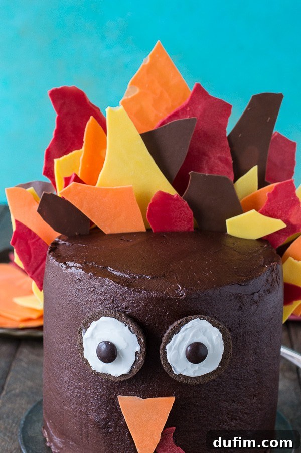 A beautifully crafted 3-layer pumpkin chocolate turkey cake, ready for Thanksgiving, with colorful chocolate shards forming its feathers.