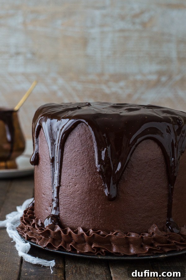 Delicious Chocolate Chocolate Cake smothered in chocolate ganache on a wooden table.