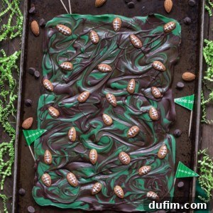 Finished Football Bark on a white plate, showcasing the chocolate, green, and almond football details.