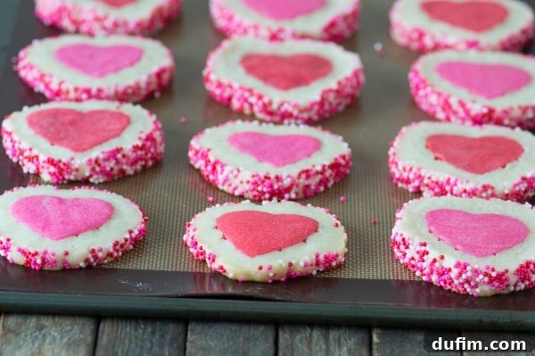 Pink Homemade Valentine’s Day Cookies on a baking sheet on top of a wooden table. 