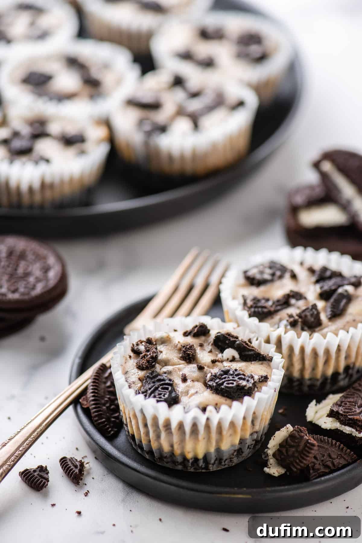 mini oreo cheesecakes on dark plate on white background