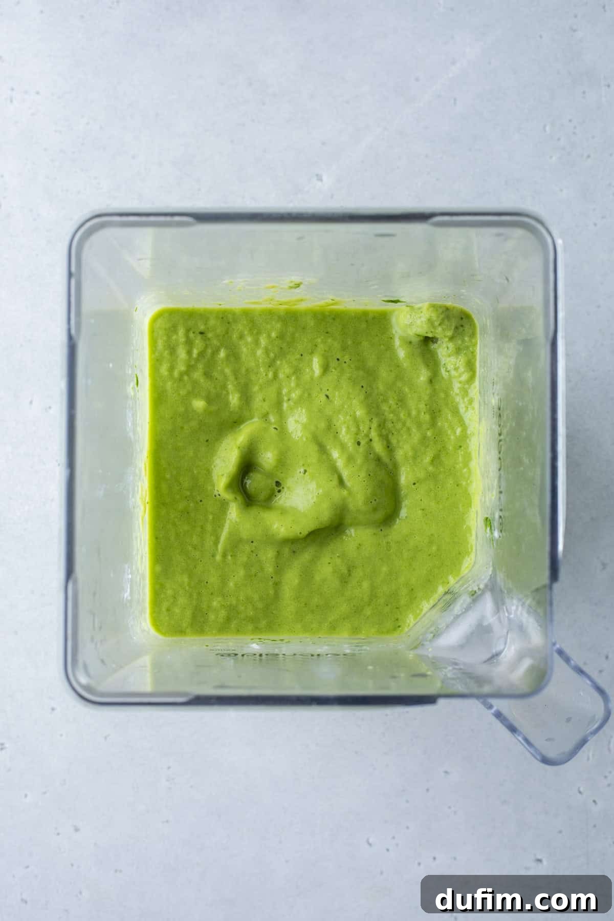The healthy green smoothie layer, with a hint of spinach, is carefully added to build up the colorful drink.