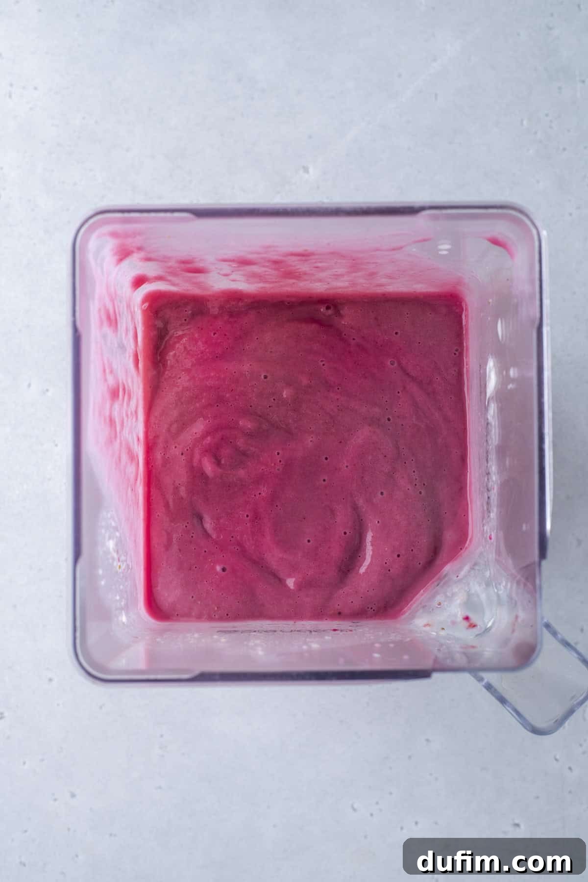 The final magenta layer, created with frozen beets, is smoothly topped on the rainbow smoothie, adding a unique and rich color.