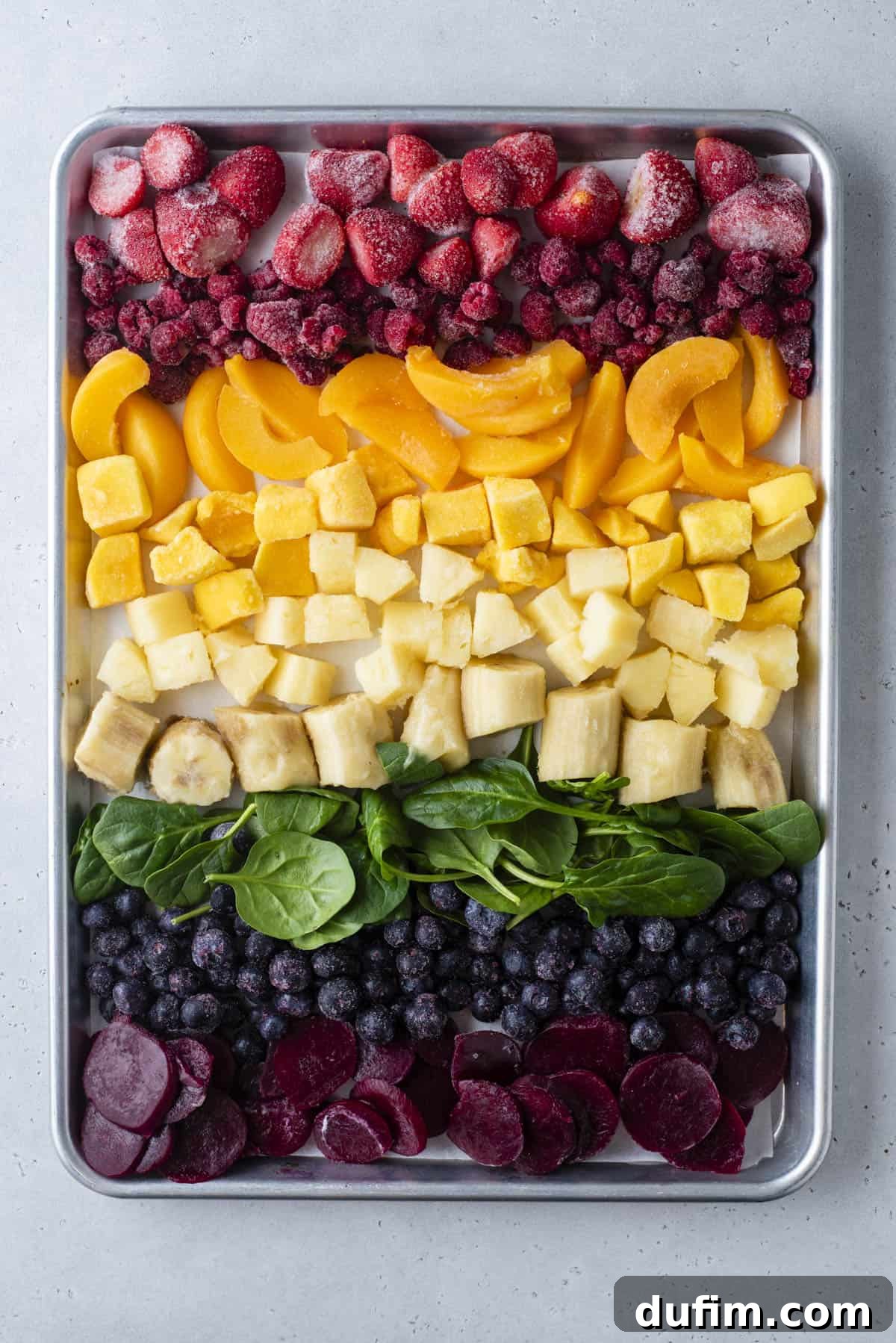 Colorburst Smoothie Delight 4 Ingredients for various layers of rainbow smoothie laid out, including frozen bananas, Greek yogurt, spinach, mixed berries, and pineapple.