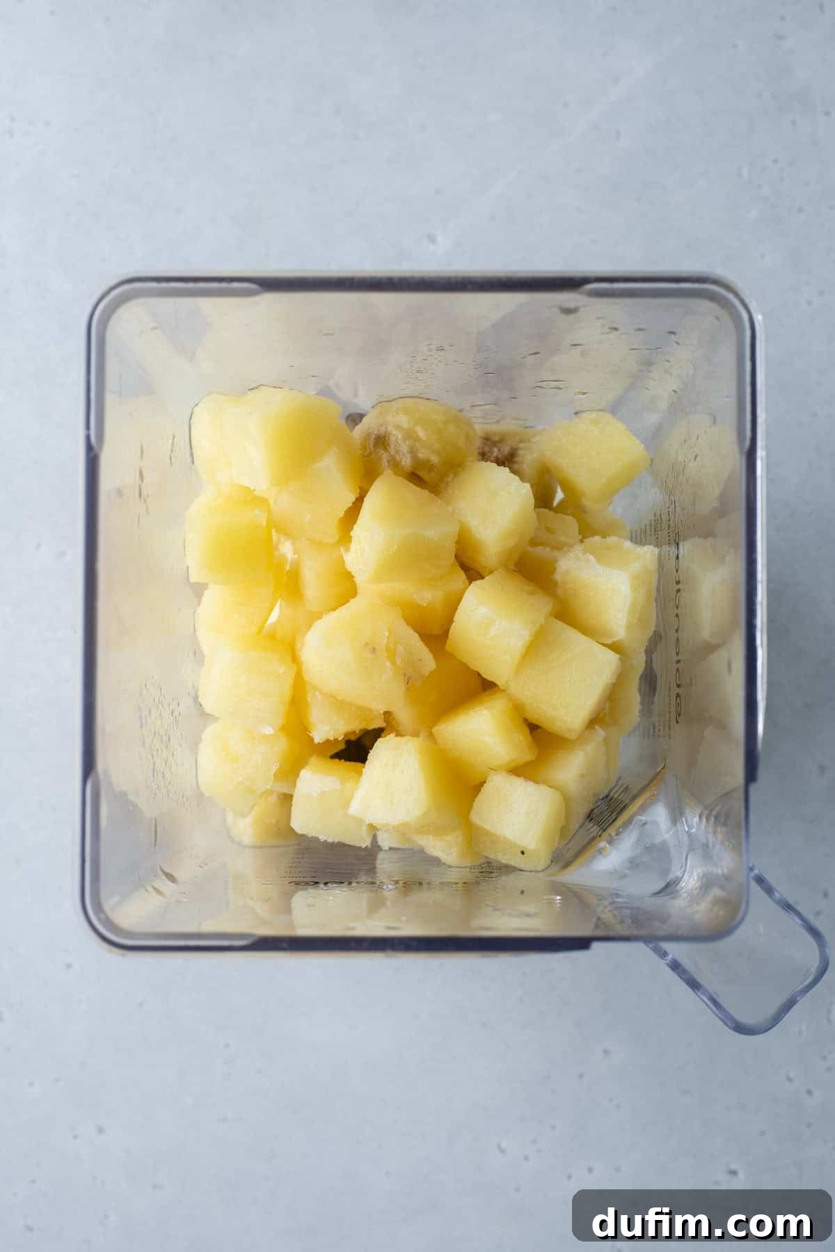 Colorburst Smoothie Delight 9 Bright yellow pineapple and banana are being blended for the third layer, promising a tropical flavor.