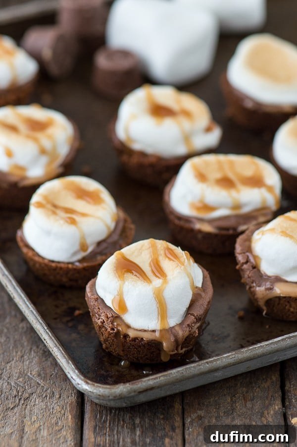 A close-up of a single Turtle S'mores Bite removed from its pan, showing the golden crust, melted Rolo, and perfectly toasted marshmallow, ready for a caramel and chocolate drizzle.