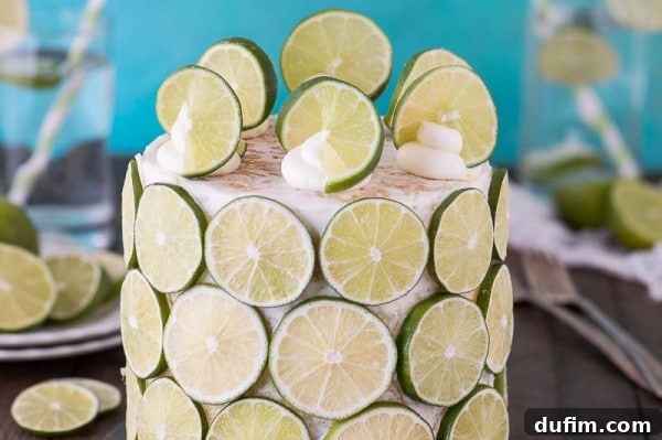 Close-up of a slice of coconut lime cake, showcasing the moist coconut cake layers and generous fresh lime buttercream between them.