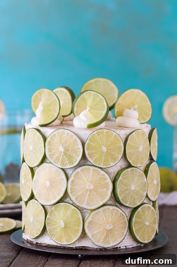A full view of the magnificent four-layer coconut lime cake, exquisitely decorated with fresh lime slices and topped with delicate buttercream swirls.