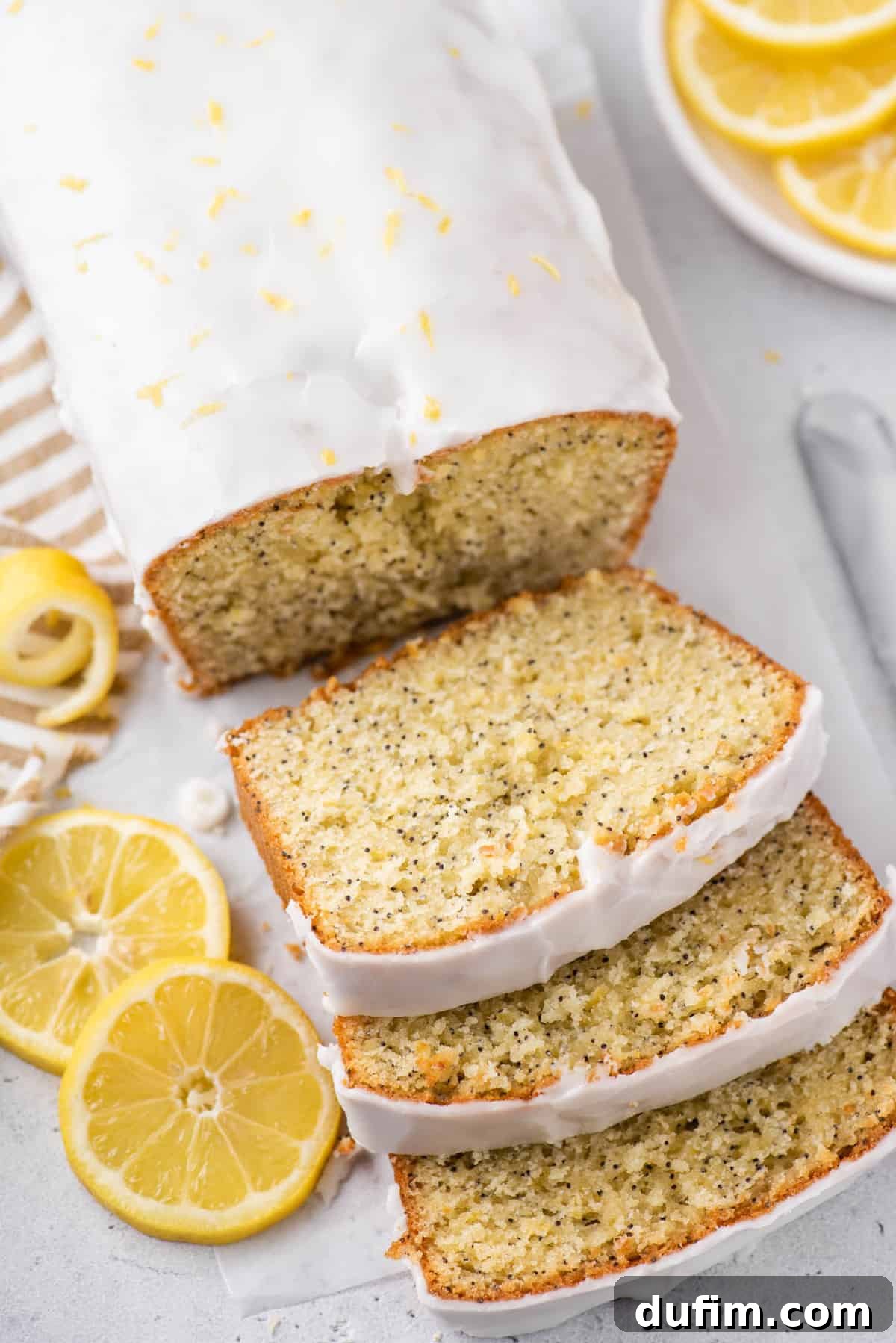 A sliced loaf of Lemon Poppy Seed Bread garnished with fresh lemon slices, ready to be served.