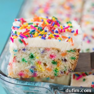 A slice of funfetti cake with white frosting and colorful sprinkles is lifted from a glass baking dish filled with even more delicious funfetti cake.