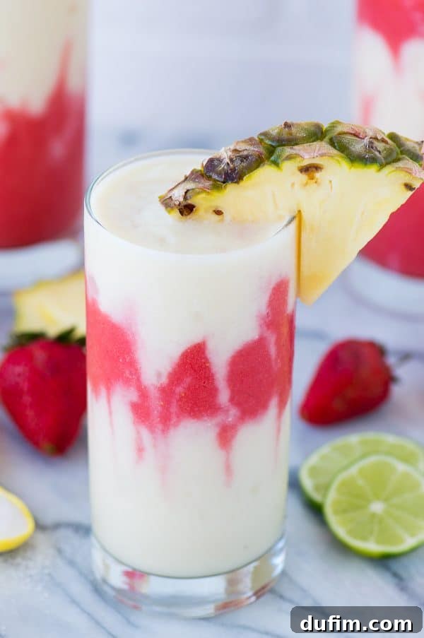 Close-up of a Miami Vice Mocktail showing the distinct layers of red strawberry daiquiri and white pina colada, garnished with fresh fruit, inviting a refreshing sip.