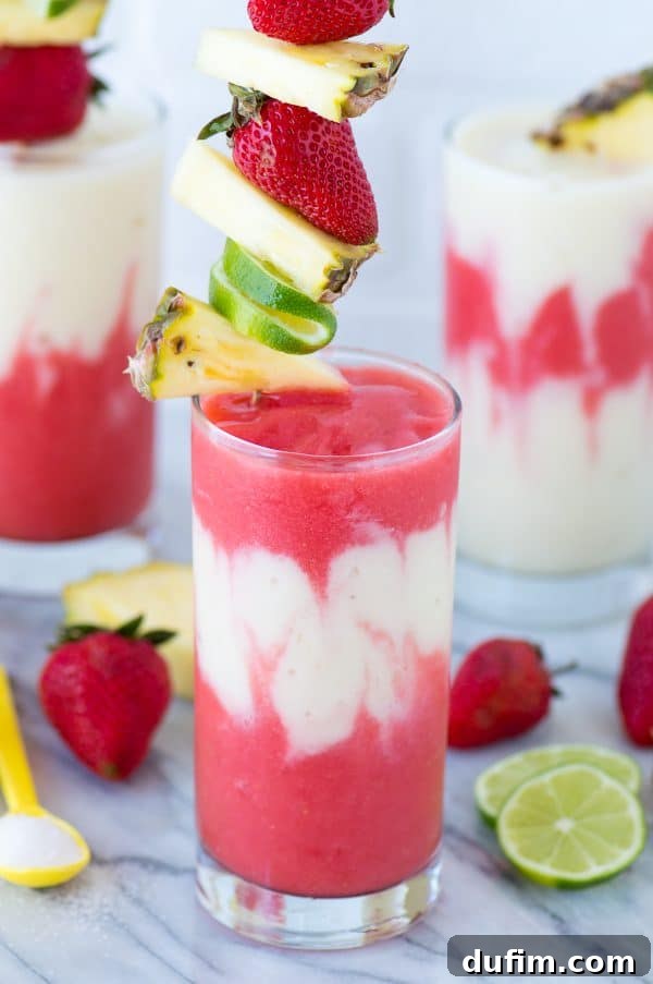 A close-up of a beautifully garnished Miami Vice Mocktail, featuring pineapple, strawberry, and a paper umbrella, emphasizing its tropical and inviting nature.
