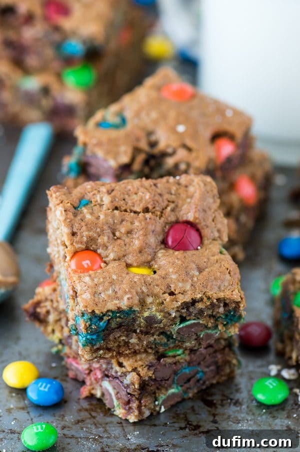A stack of perfectly cut healthier monster cookie bars, showing off their thickness and delicious layers.