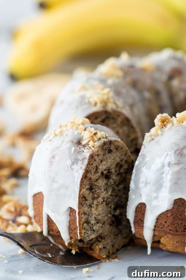 One-bowl banana nut bundt cake generously drizzled with a smooth vanilla bean glaze and garnished with chopped walnuts.