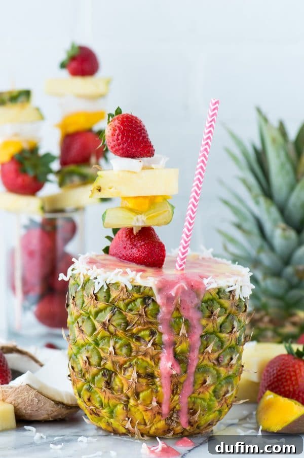 Layering pineapple coconut and strawberry smoothies in a pineapple cup