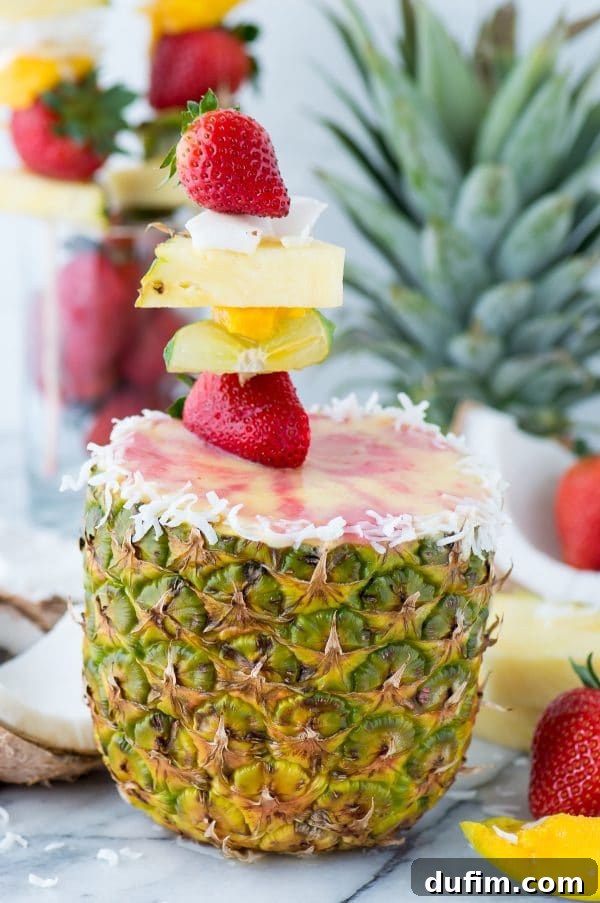 Fully garnished pineapple strawberry smoothie in a carved pineapple