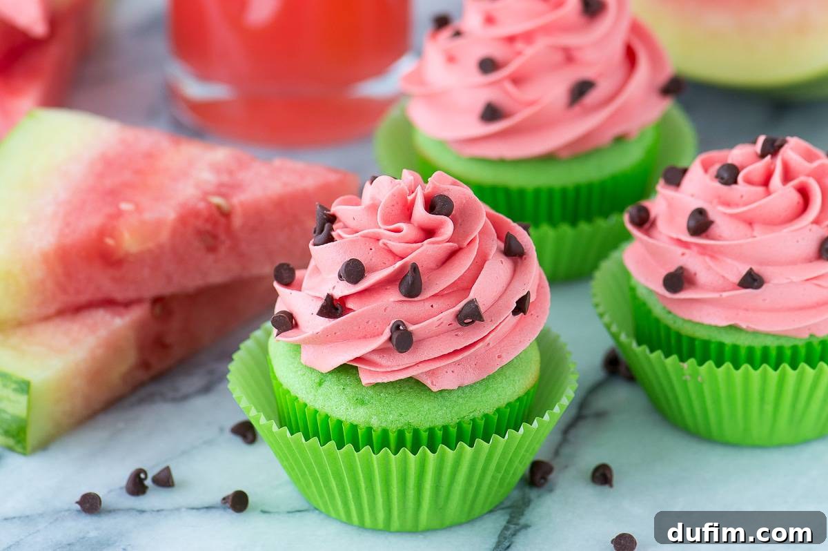 Watermelon Burst Cupcakes 4 A trio of green cupcakes with perfectly swirled pink watermelon frosting and miniature chocolate chips, set against a smooth marble surface.