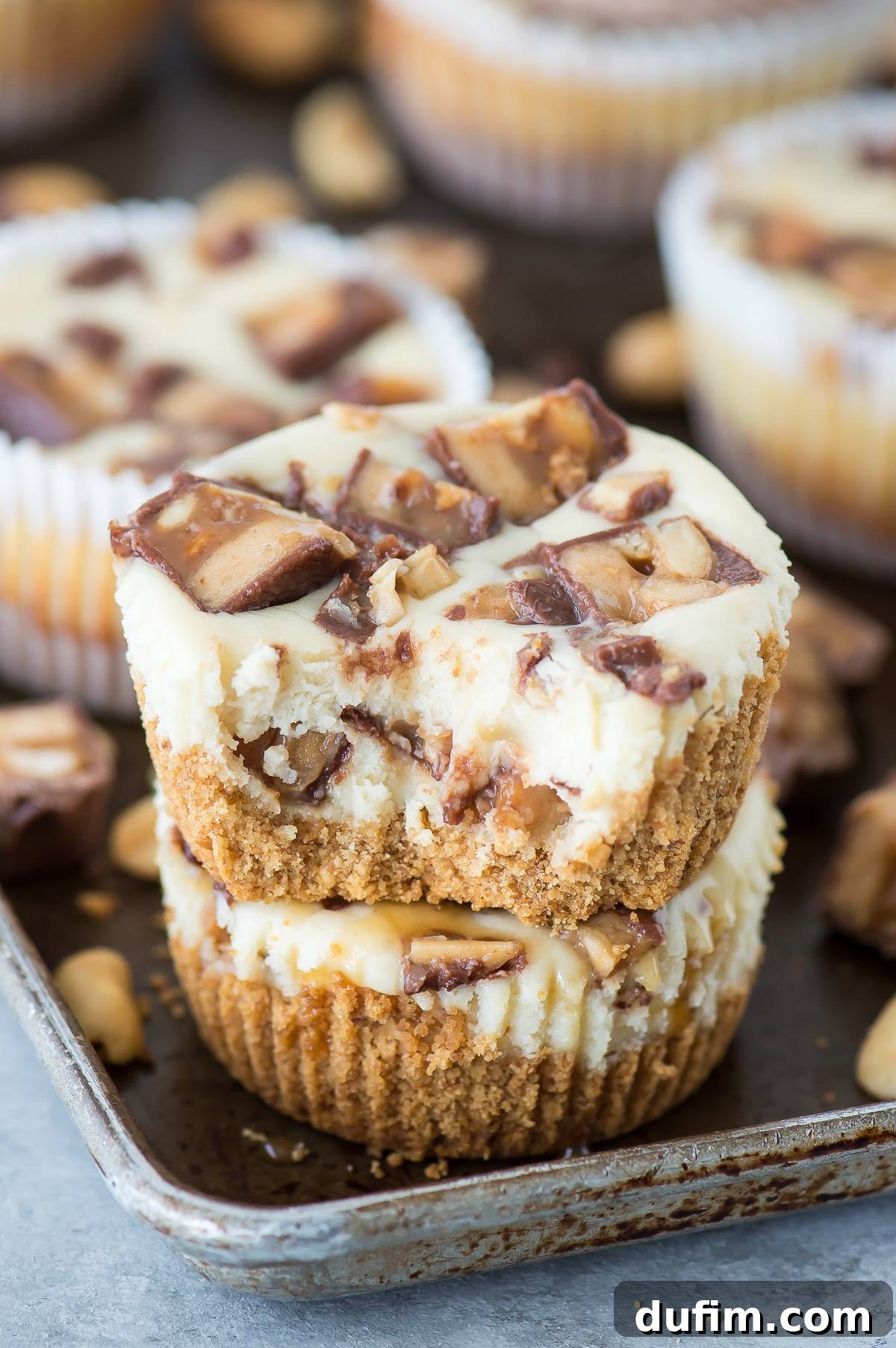 A mini Snickers cheesecake with a bite taken out, showing the creamy filling and a rich crust.