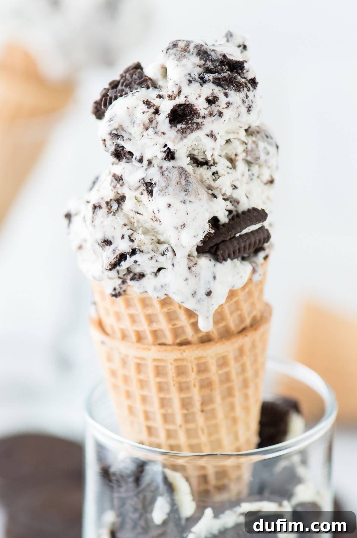 Two waffle cones brimming with Easy Oreo Ice Cream, garnished with extra crushed Oreos, promise a delightful and refreshing treat.
