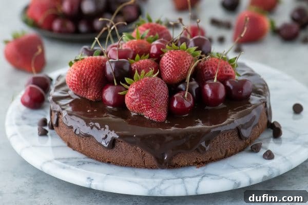 Luscious Berry Mud Cake 2 Decadent classic chocolate mud cake with glossy chocolate ganache, adorned with juicy strawberries and cherries, ready to be served.