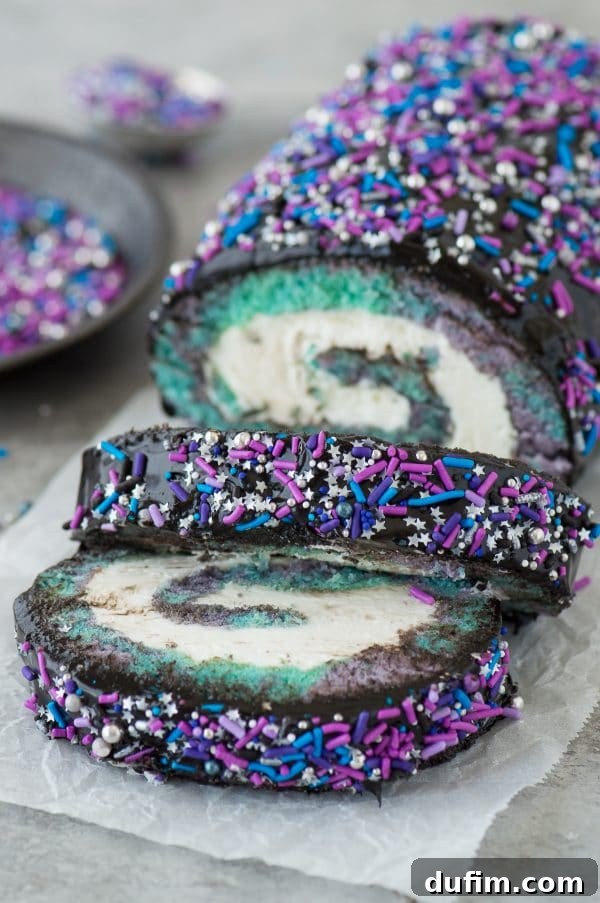 Stunning multi-colored galaxy cake roll slice, revealing vibrant purple, blue, teal, and black swirls, with a luscious black chocolate ganache coating and sparkly sprinkles.