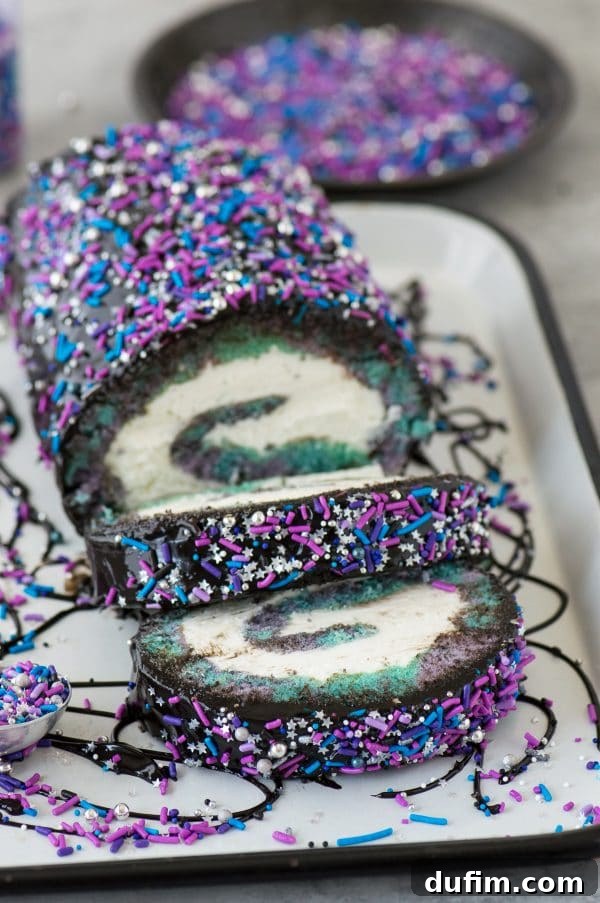 Close-up of the galaxy cake roll, showcasing the beautiful swirling colors of the cake with its creamy filling and the glossy black chocolate ganache topping adorned with star-like sprinkles.