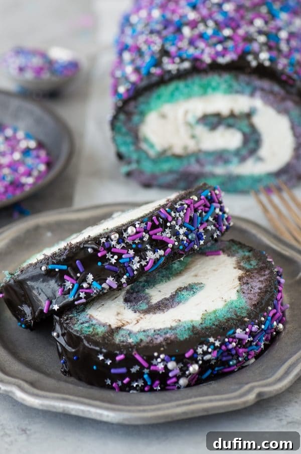An overhead shot of the galaxy cake roll, highlighting the intricate swirls of color and the generous application of sparkling sprinkles over the dark ganache.