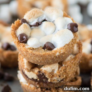 Three stacked 5-ingredient indoor S’mores Cups surrounded by other delicious s'mores cups on a baking dish, illustrating their perfect form.