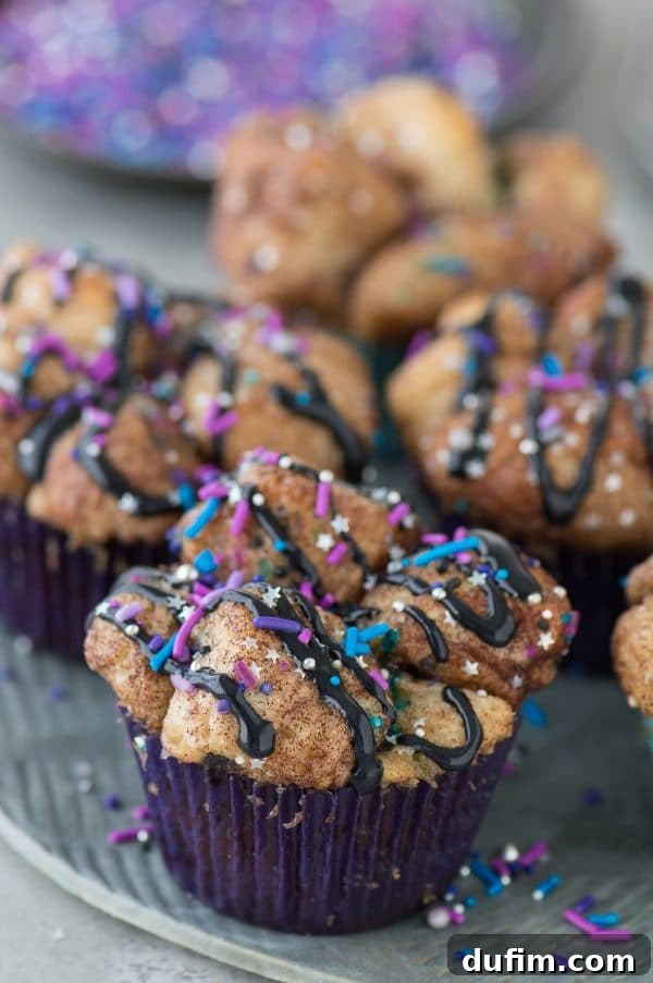Galaxy Monkey Bread Muffins topped with a black cream cheese glaze and colorful star sprinkles, presenting an out-of-this-world dessert.