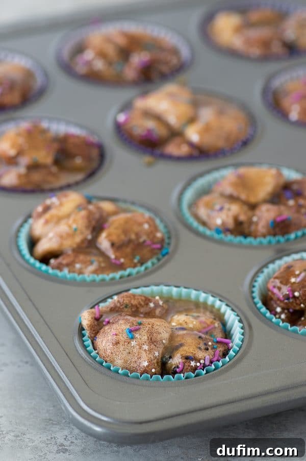 A stunning close-up of baked Galaxy Monkey Bread Muffins, topped with a dark, glistening glaze and scattered sprinkles.