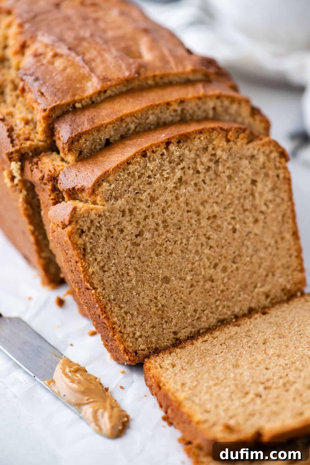 Sliced loaf of moist peanut butter bread on a white background, ready to be enjoyed