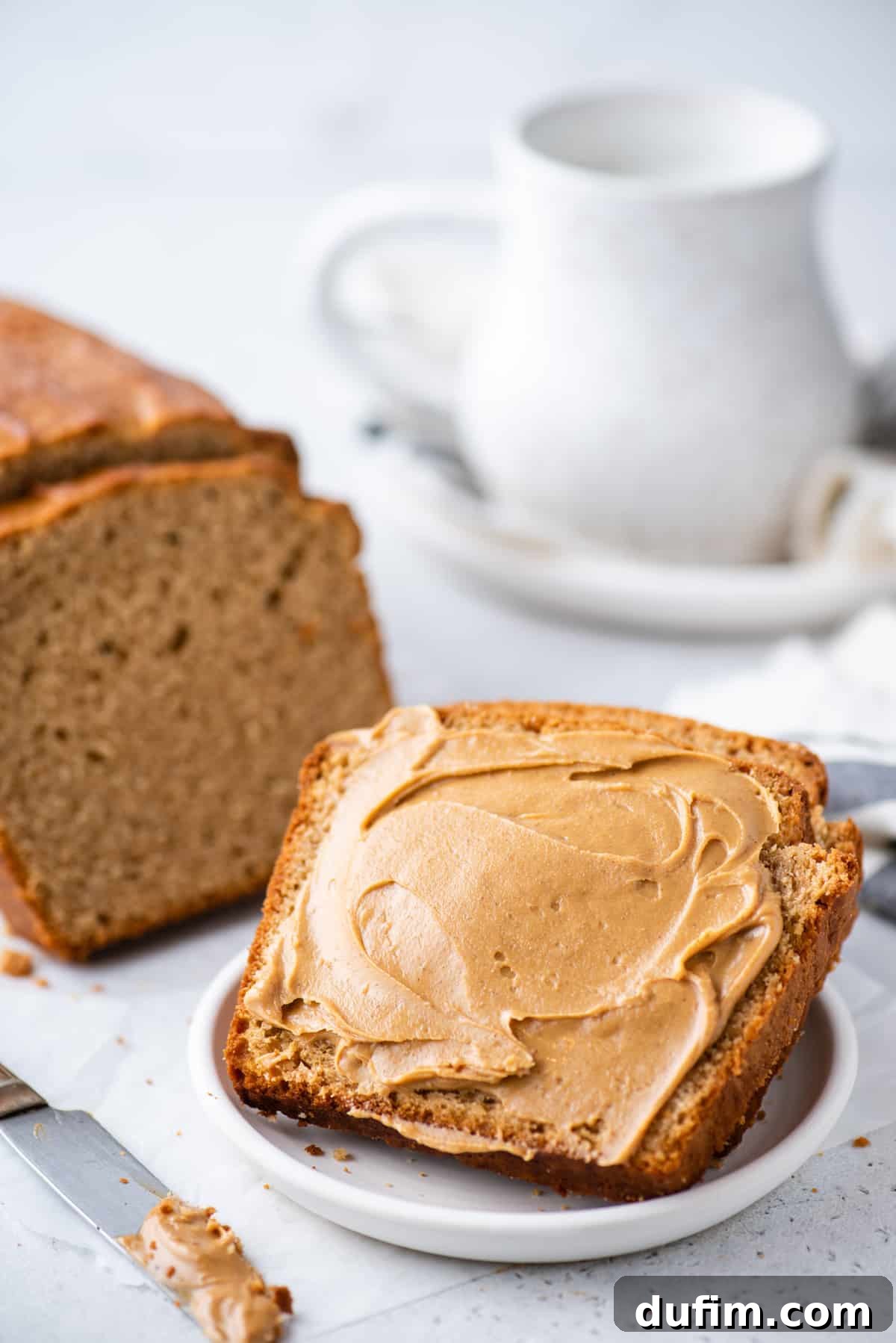 Close-up of a slice of peanut butter bread with peanut butter spread on top, on a white plate
