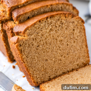 Sliced loaf of homemade peanut butter bread on a cutting board, showing a soft and moist texture with a golden-brown crust. A knife with a dollop of creamy peanut butter rests nearby.