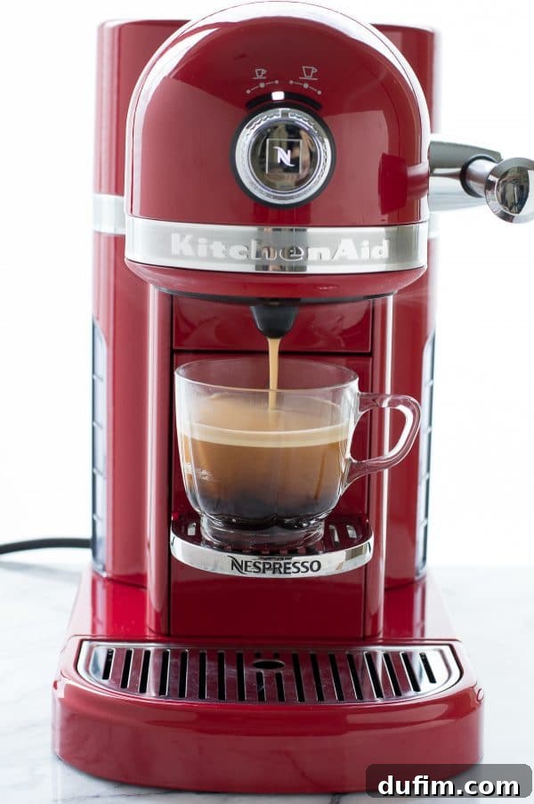 KitchenAid Nespresso Machine sits beside a platter of freshly baked Espresso Coffee Cake, highlighting the rich colors and textures.