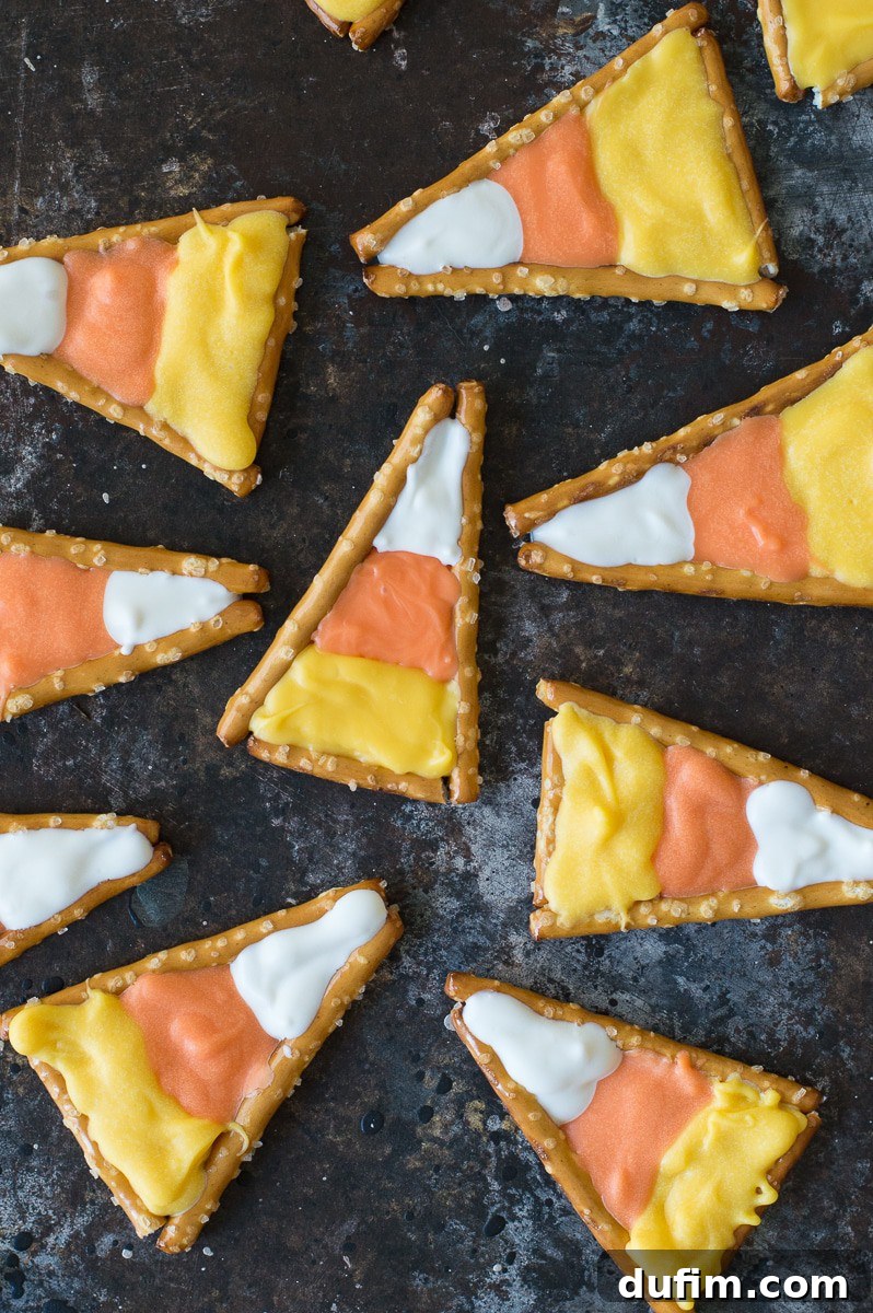 Sweet and Salty Candy Corn Twists 3 A close-up of multiple candy corn pretzels, showcasing the smooth, colorful candy melt layers and the pretzel crunch.