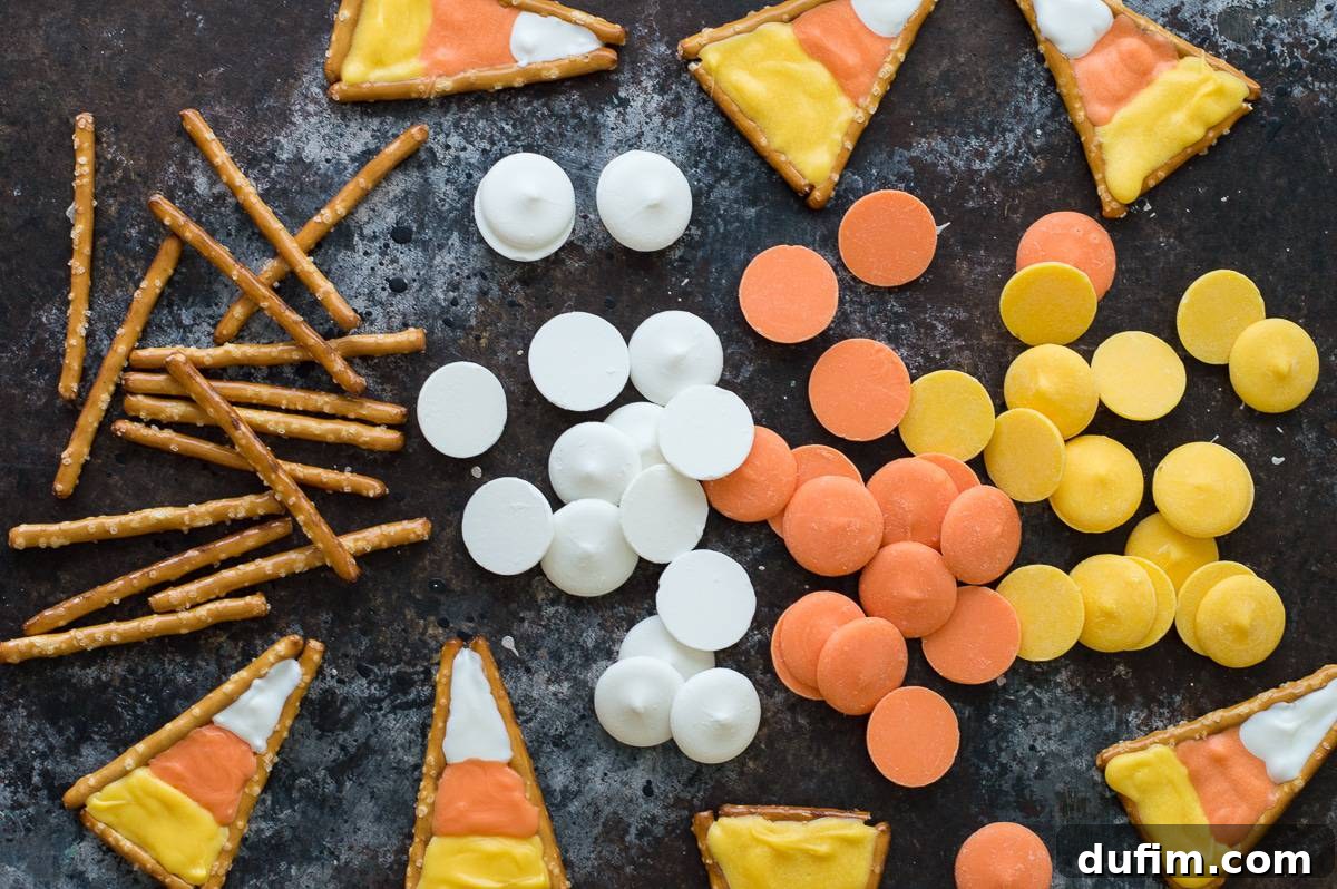 Sweet and Salty Candy Corn Twists 4 A birds-eye view of several neatly arranged candy corn pretzels on a sheet of parchment paper, highlighting their perfect triangular shape and distinct color bands.
