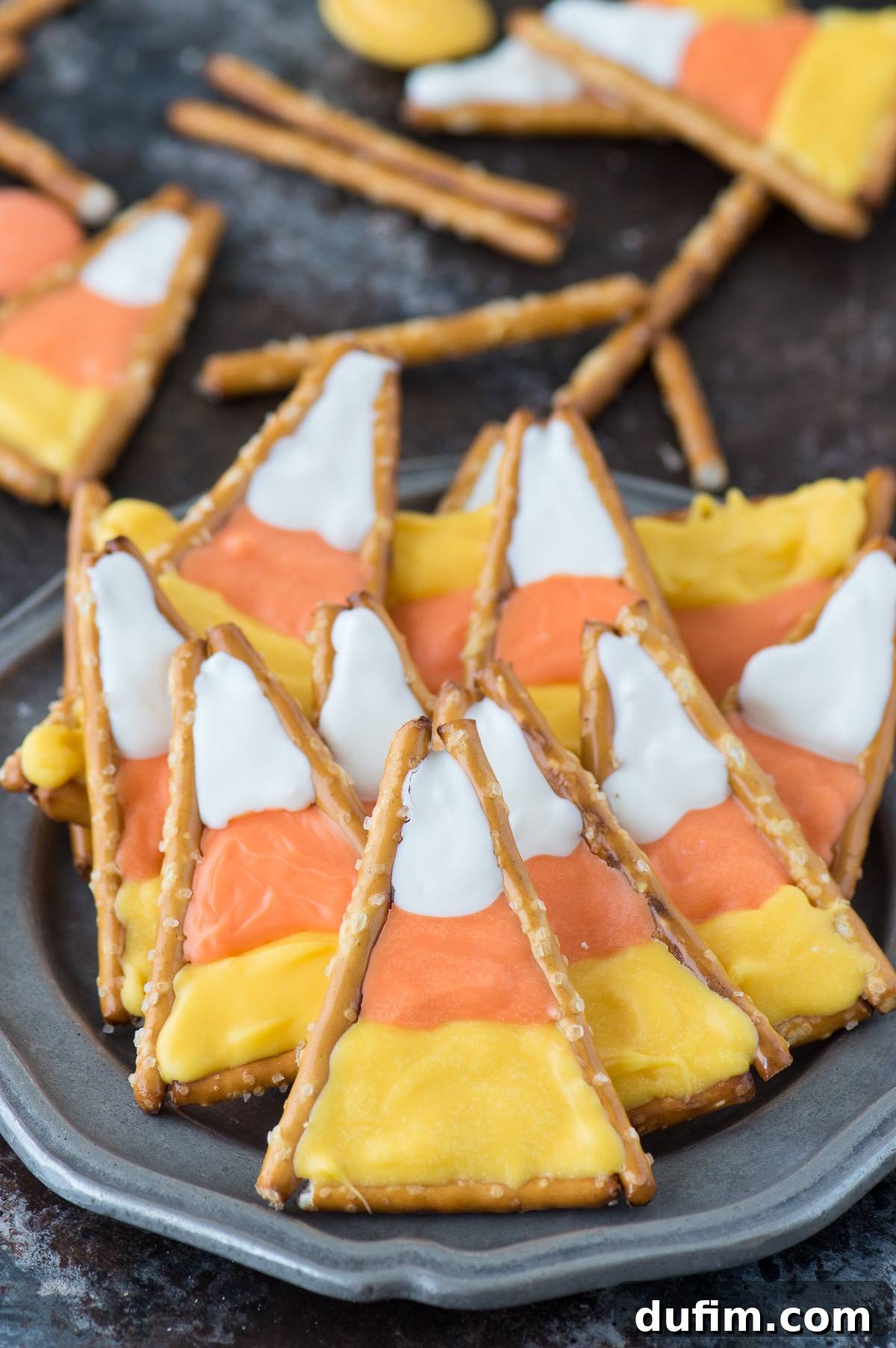 Sweet and Salty Candy Corn Twists 5 Pretzel sticks arranged on wax paper to form small triangular candy corn outlines, ready for candy melt filling.