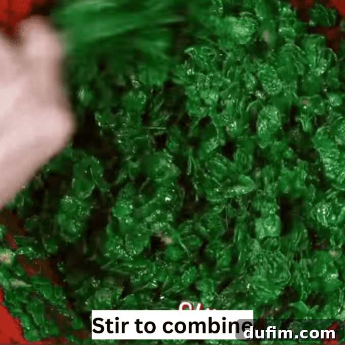 Golden No-Bake Wonders 8 Green marshmallow-coated cornflakes in a spacious mixing bowl, after being perfectly combined, awaiting transformation into festive Christmas wreaths.